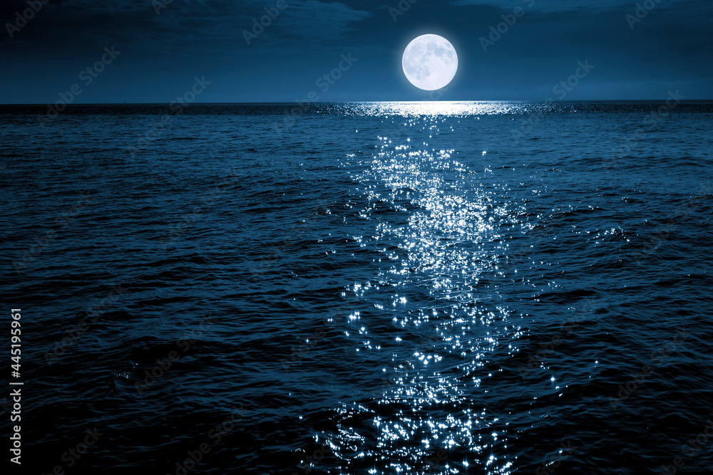 这轮蓝色的满月在平静的海面上明亮地升起，在海浪中闪闪发光