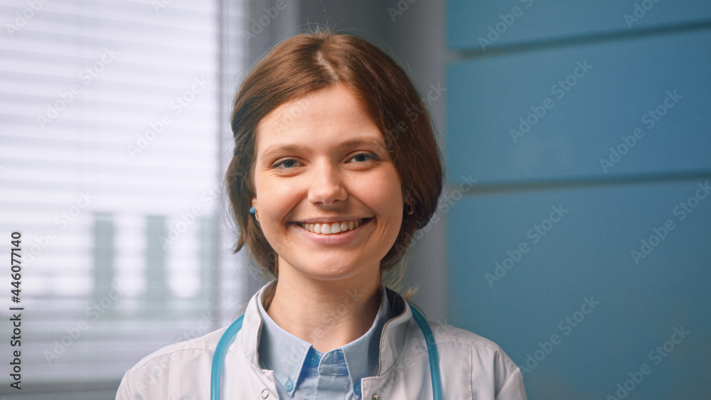 漂亮开朗的年轻女性全科医生站在蓝色的hos面前，看起来很直，面带微笑