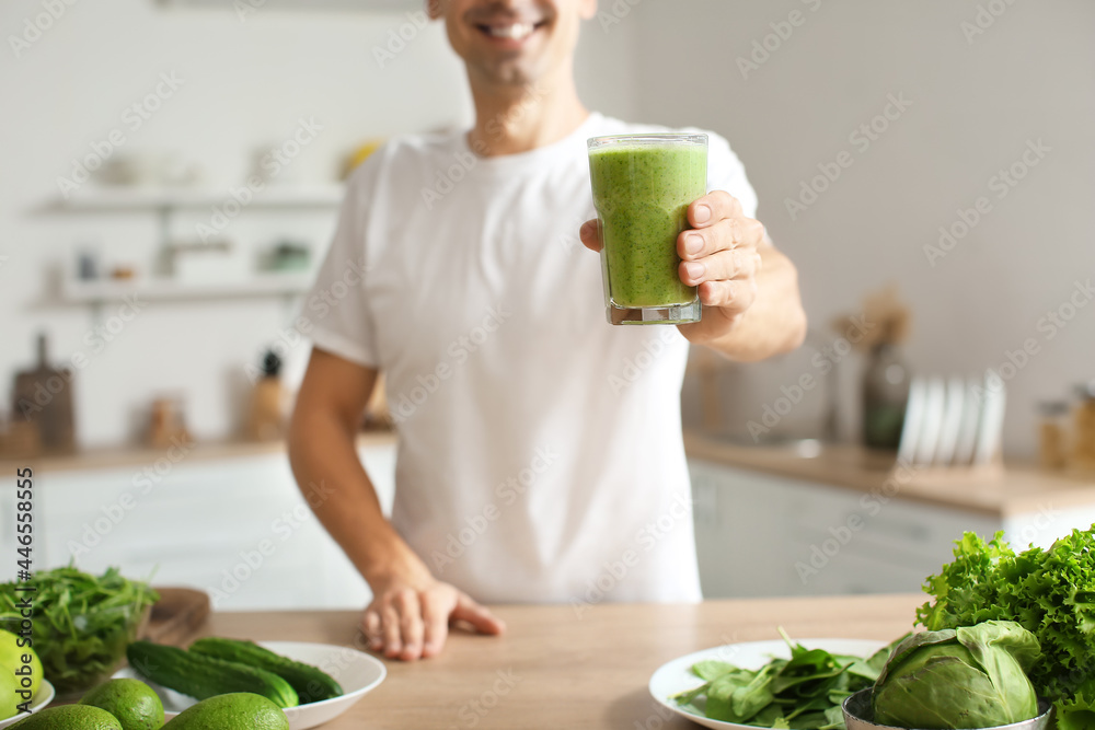 年轻人在厨房里喝着一杯健康的绿色奶昔