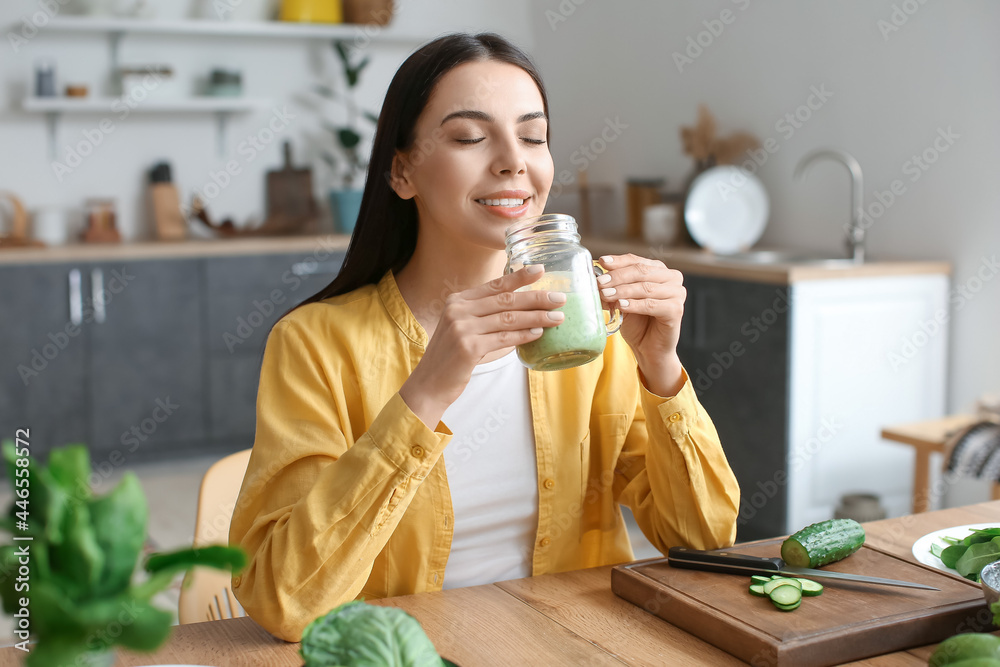 年轻女性在厨房喝健康的绿色冰沙