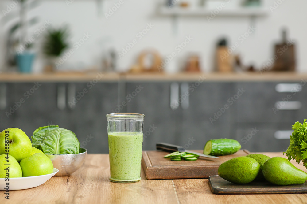 Glass of healthy smoothie and ingredients on kitchen table, closeup