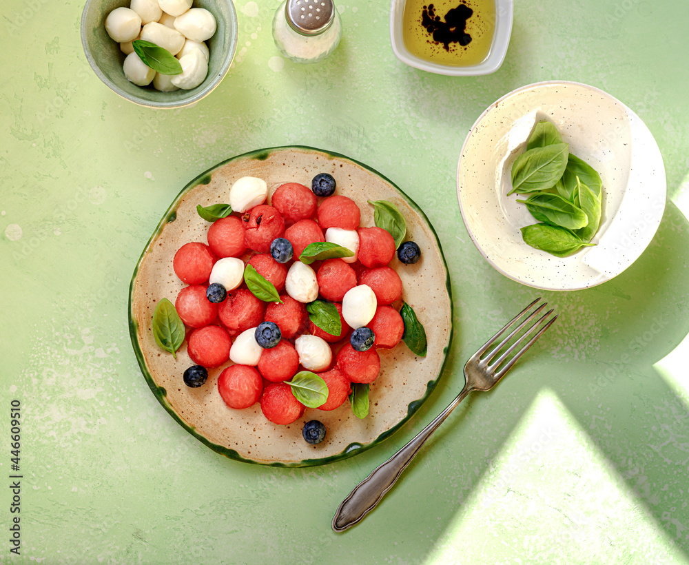 西瓜沙拉配马苏里拉奶酪、蓝莓和绿色背景的新鲜罗勒叶。Cap