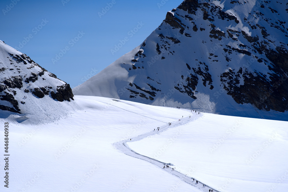 Tourists walking on snow trail at Jungfraujoch on a sunny summer day morning. Photo taken July 20th,