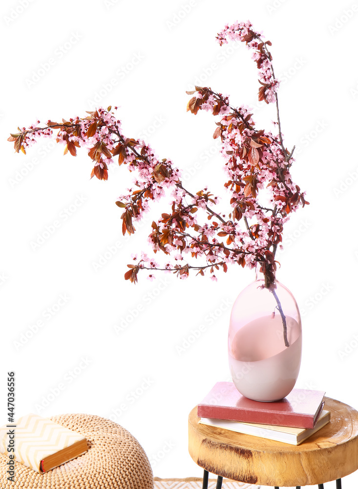 白色背景下，花瓶上有盛开的树枝和桌子上的书