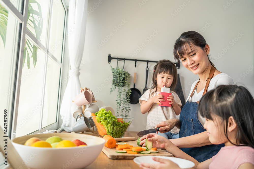 亚洲美女妈妈和两个年幼的女儿一起做蔬菜沙拉