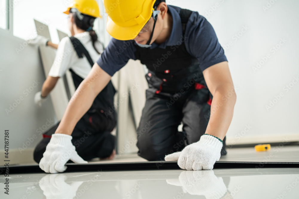 亚洲工匠工人在家里的地板上安装强化木地板