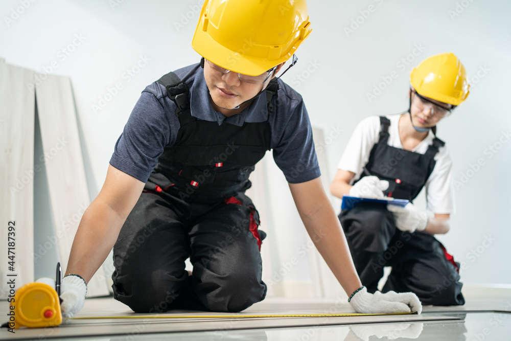亚洲建筑工人男性在走廊上使用卷尺镶木地板。
