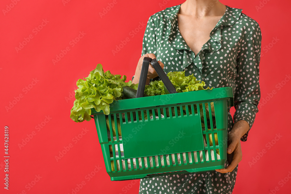 年轻女子拿着彩色背景的新鲜蔬菜购物篮