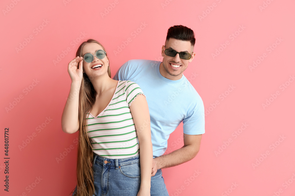 一对年轻夫妇在彩色背景上戴着时尚的太阳镜