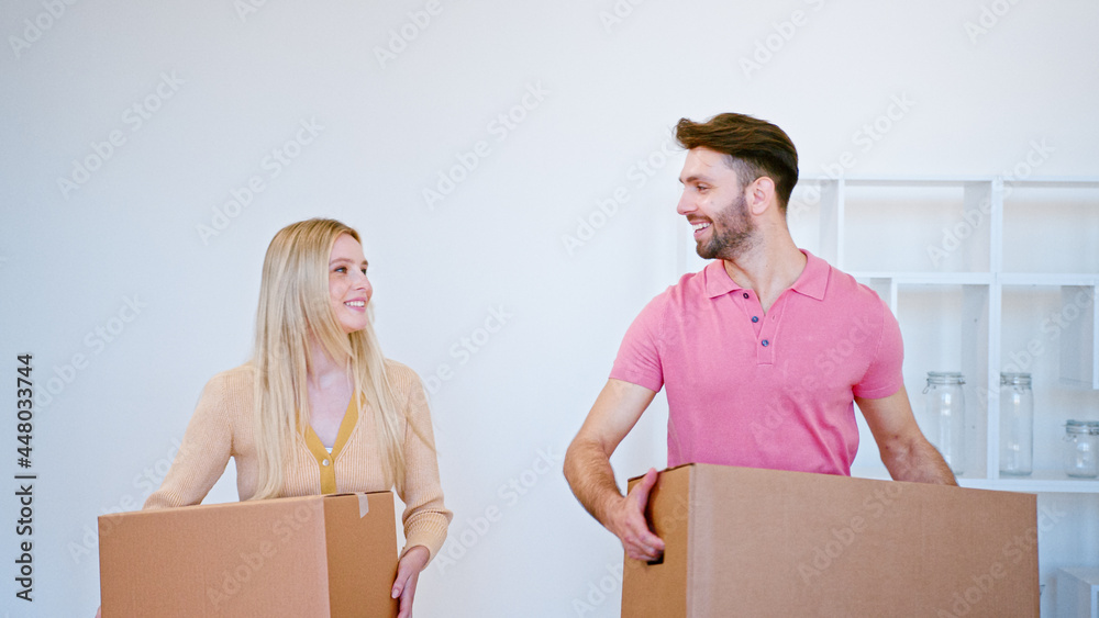 Amazed couple of newlyweds long haired blonde and smiling guy carry large cardboard boxes