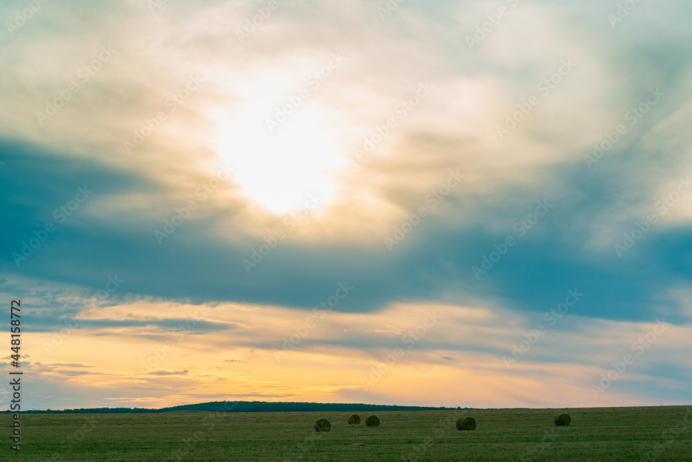 日落时太阳穿过的田野和云层。