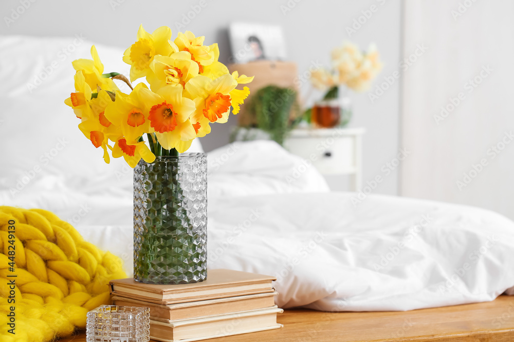 房间床头柜上放着水仙花和书的花瓶