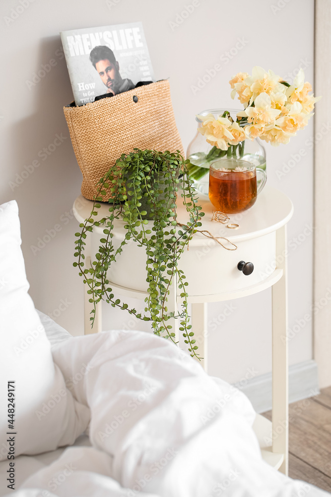 房间床头柜上放着水仙花和一杯茶的花瓶