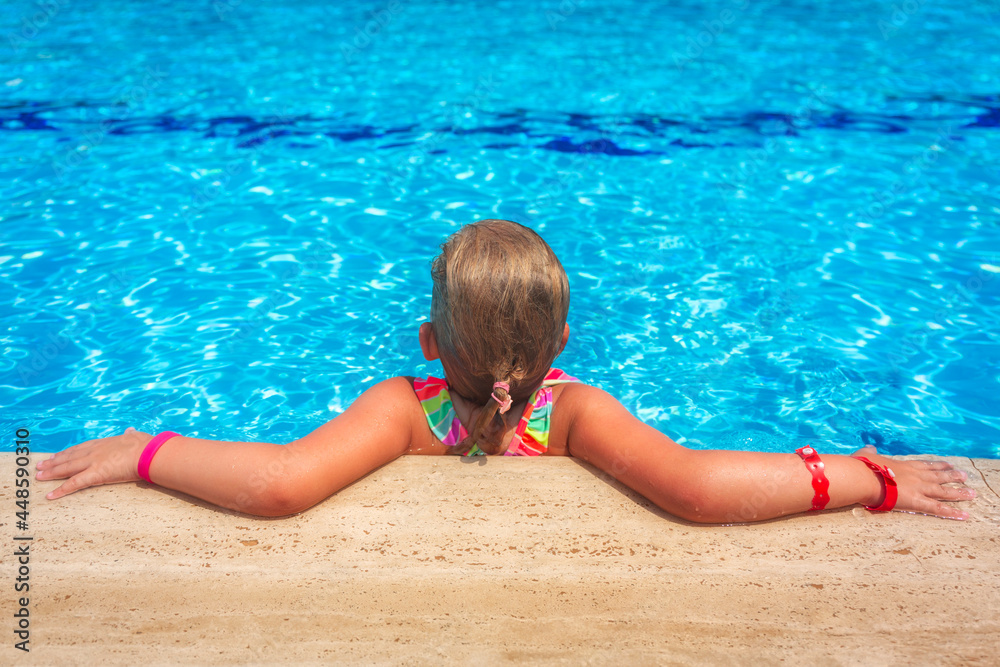 暑假，可爱的小女孩在游泳池的水晶水中放松。