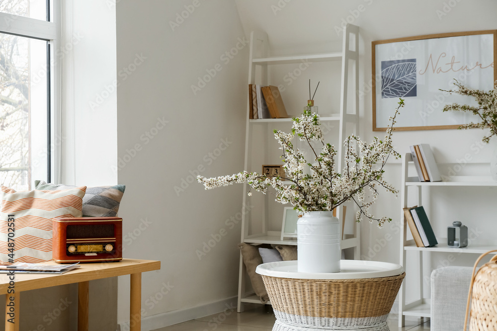 Vase with blossoming branches in interior of modern living room