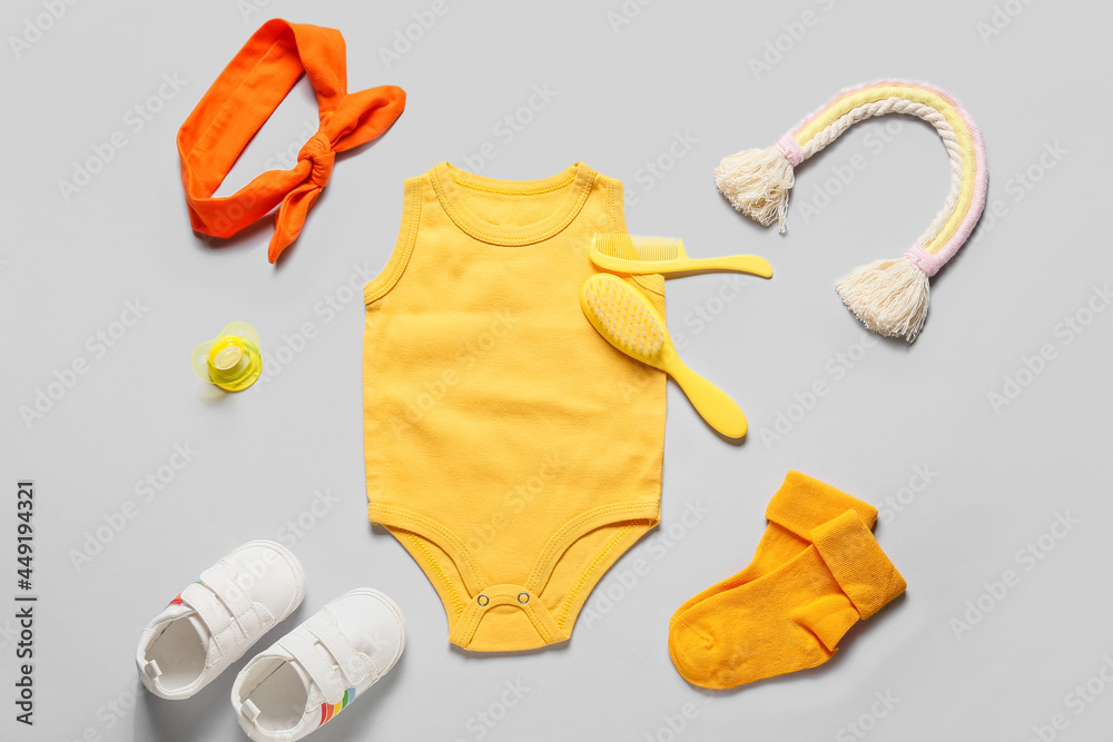 灰色背景的婴儿衣服、鞋子、玩具和配件