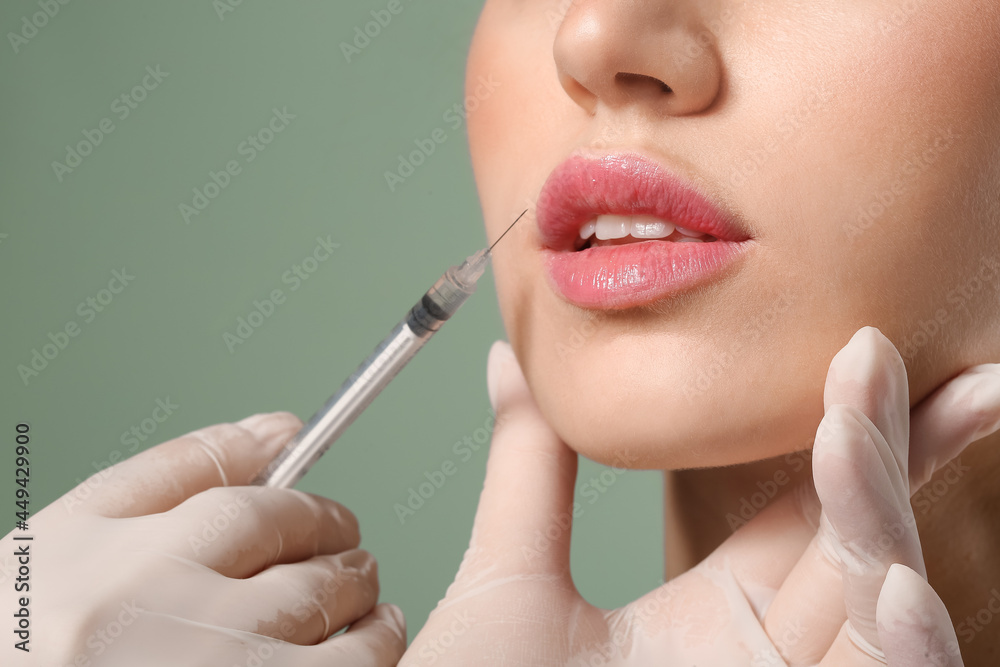 年轻女性在彩色背景下接受唇部填充物注射，特写
