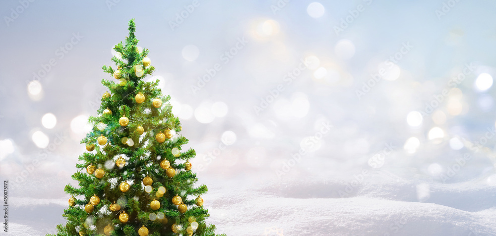 美丽的节日淡雪背景。圣诞树前面装饰着金球