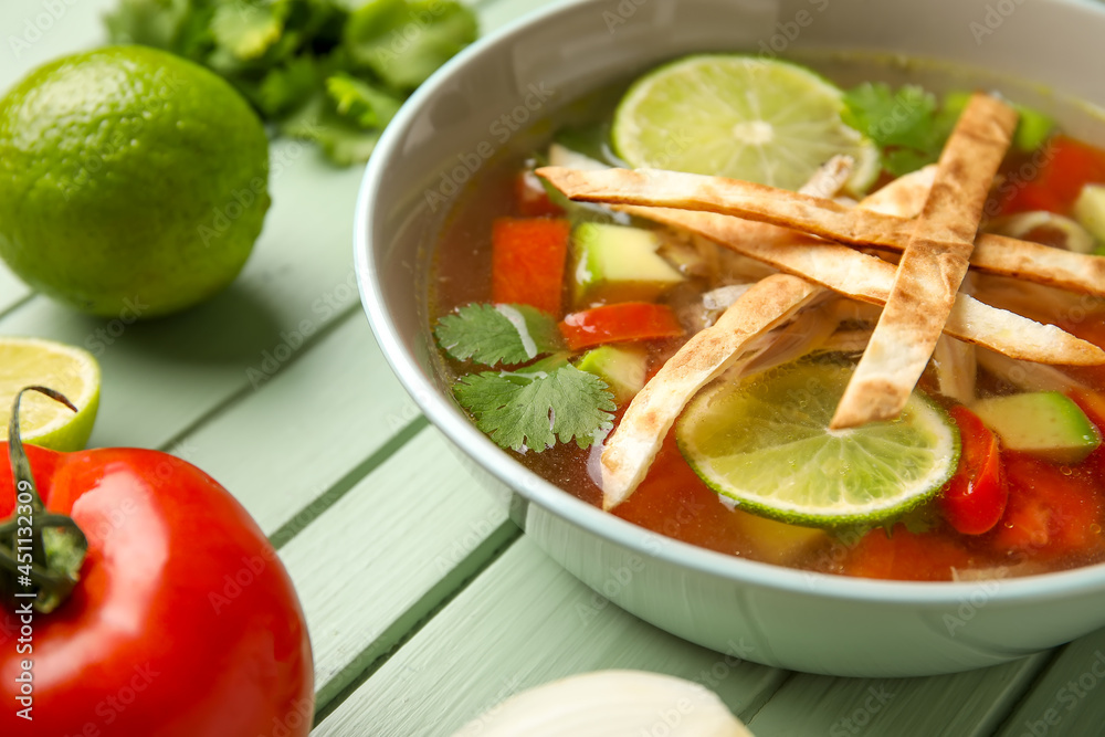 一碗美味的Sopa de Lima汤，彩色木质背景，特写