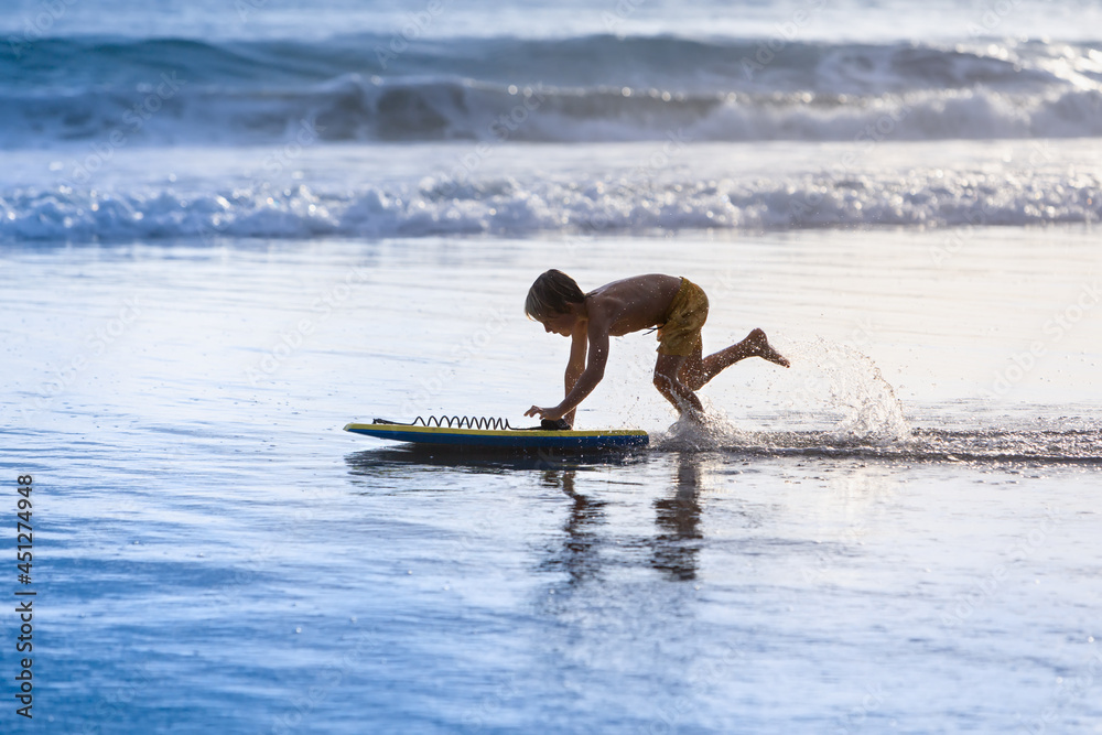 带着冲浪板的男孩在海边玩得很开心