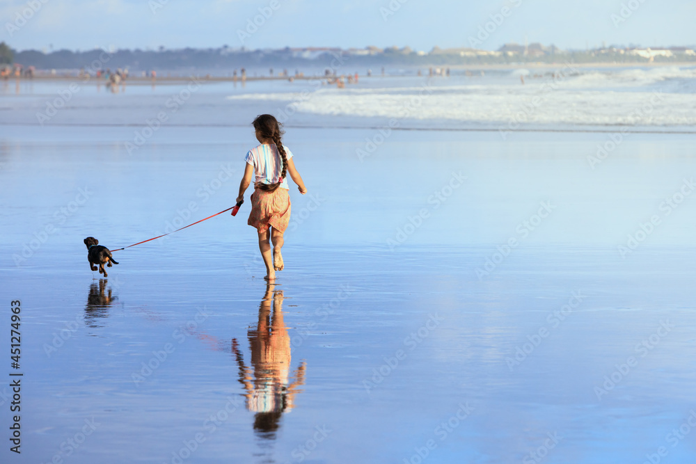 女孩和达克斯猎犬玩得很开心，海边跑