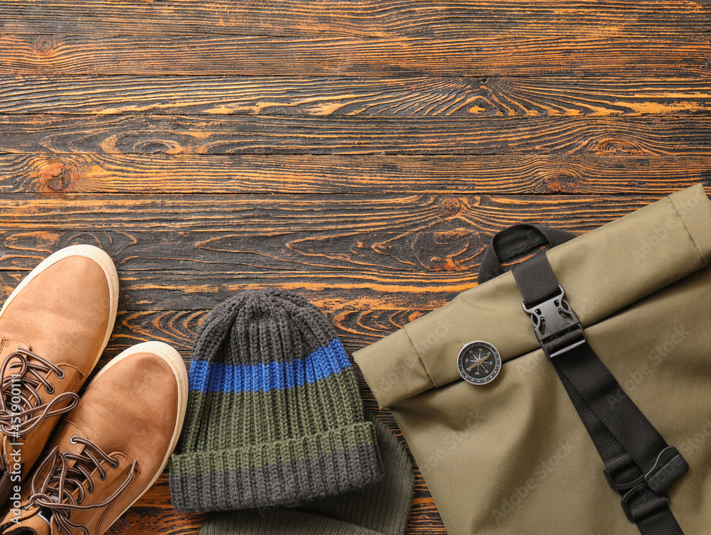 木质背景的时尚男性帽子、鞋子、背包和指南针