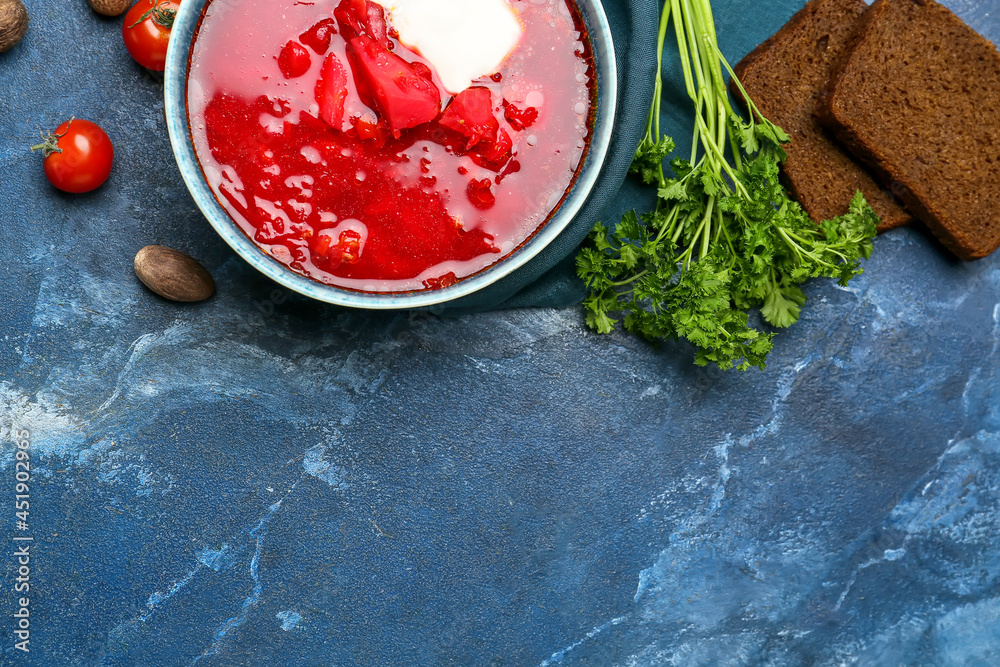 Bowl with tasty borscht, slices of fresh bread and ingredients on color background