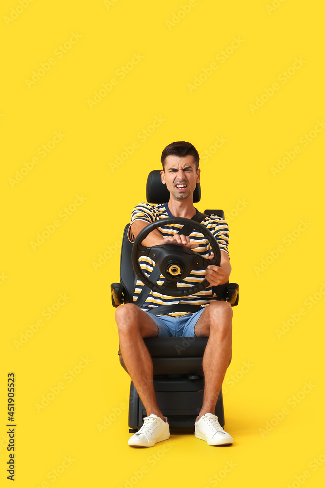愤怒的男子坐在汽车座椅上，方向盘在彩色背景上