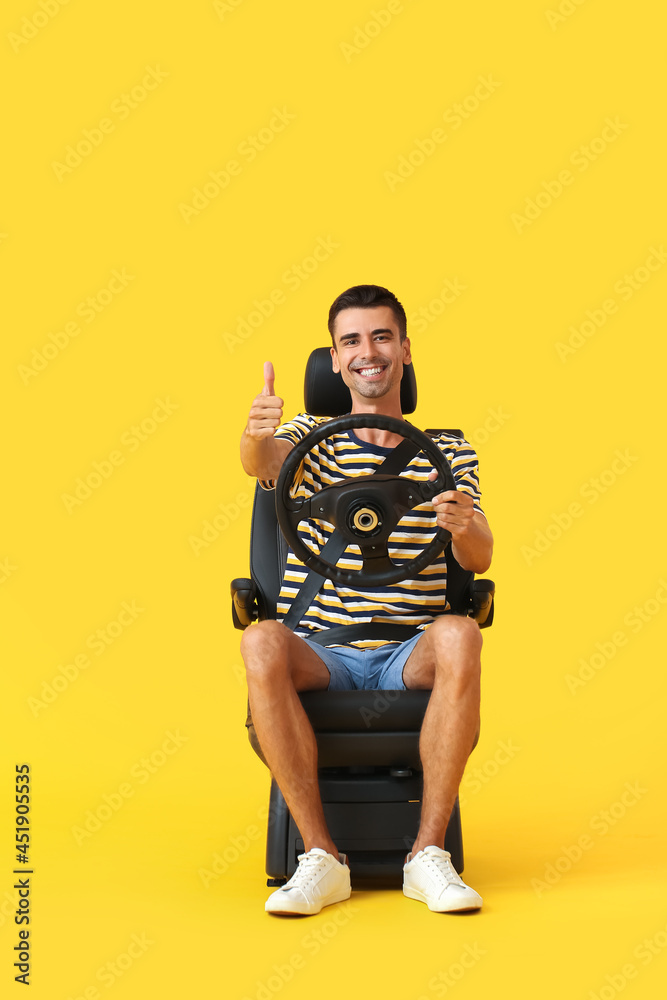 男子坐在汽车座椅上，方向盘在彩色背景上显示拇指向上
