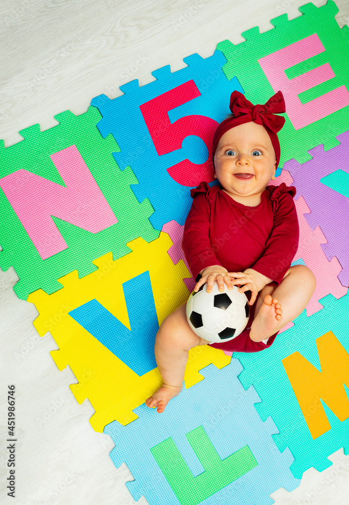 带着字母和足球在地毯上的女婴