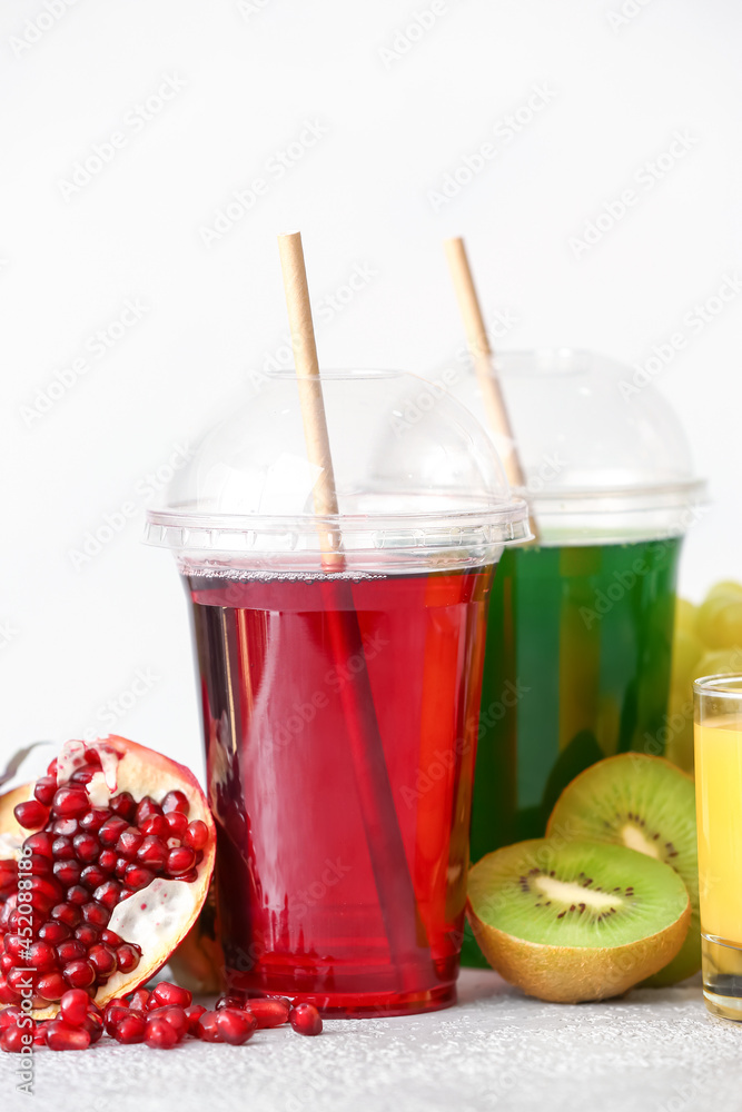 浅色背景下有健康果汁和水果的塑料杯