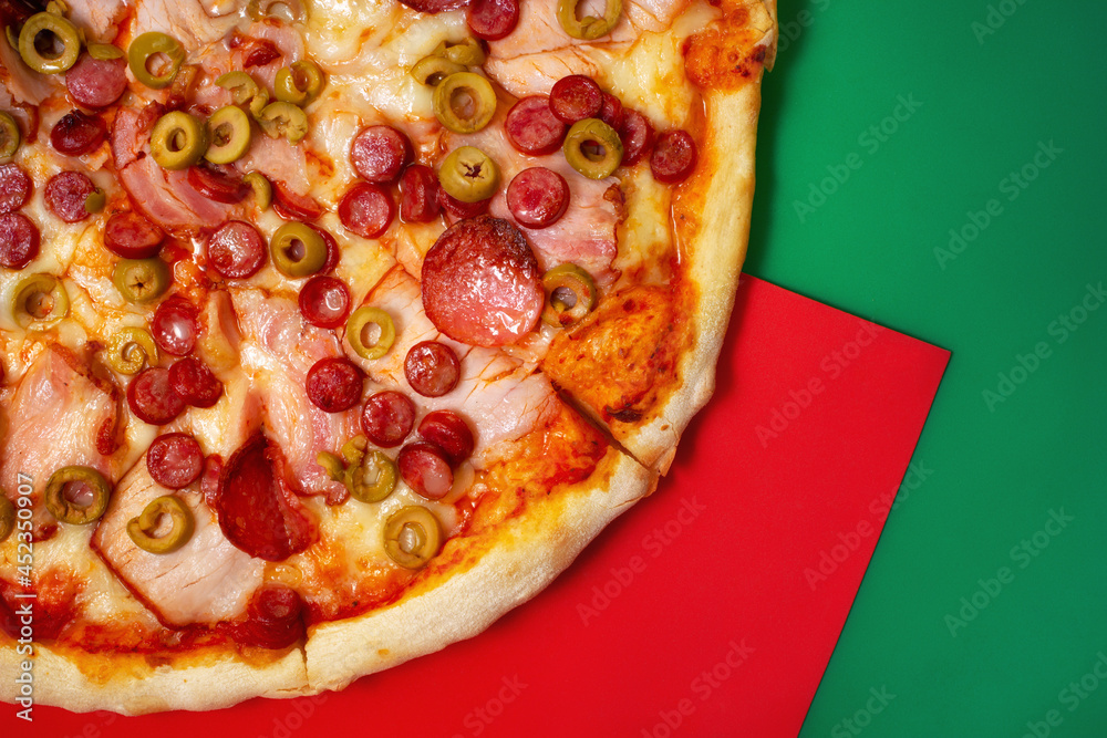 红色和绿色背景的火腿和烟熏香肠意大利披萨，带有复制空间区域