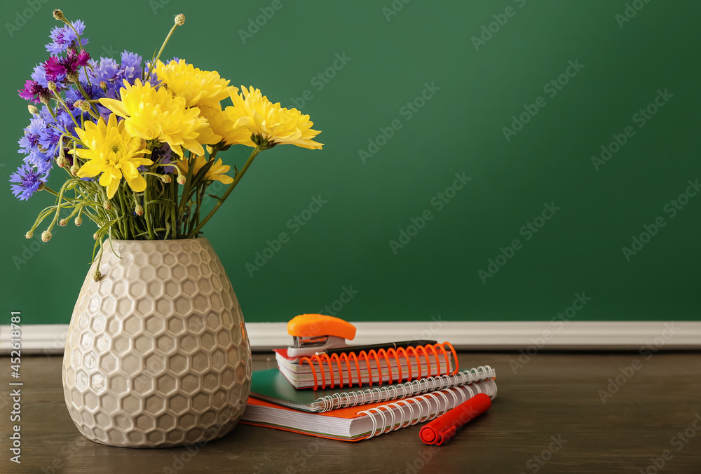 教室桌子上放着漂亮的鲜花和文具的花瓶。教师节庆祝活动