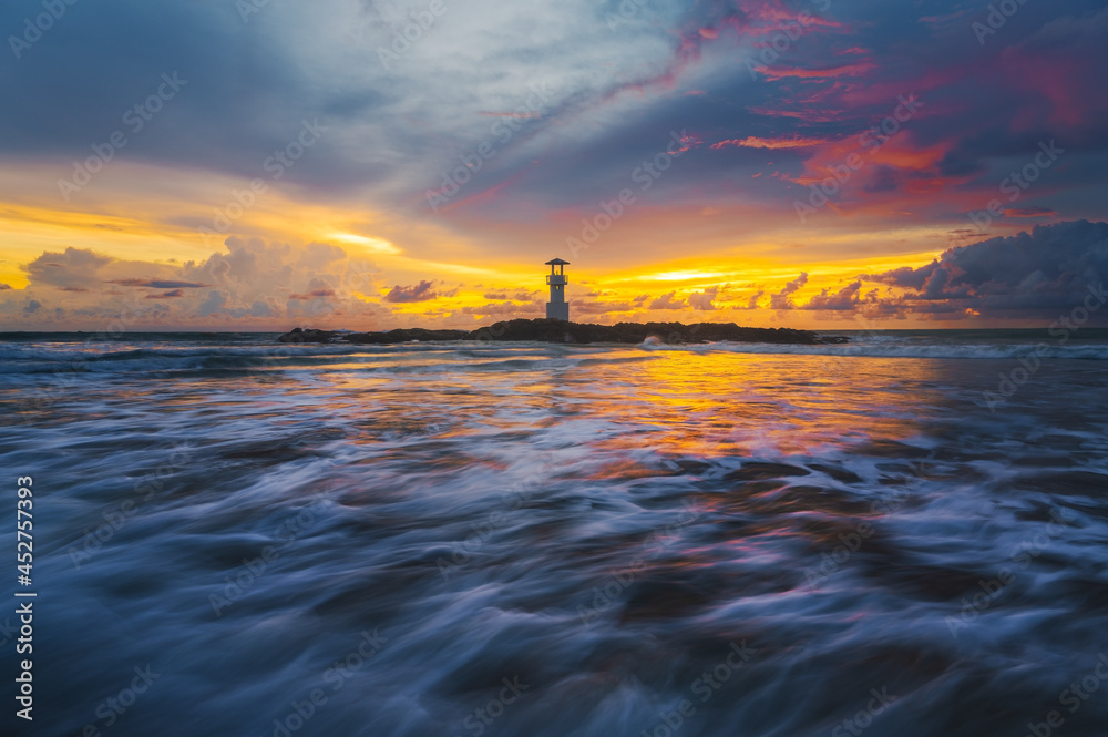 阴天的海景，长时间暴露的波浪纹理和甲米日落时的灯塔，