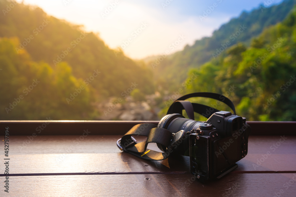 Photography theme, Camera on wooden table against mountain background at sunset