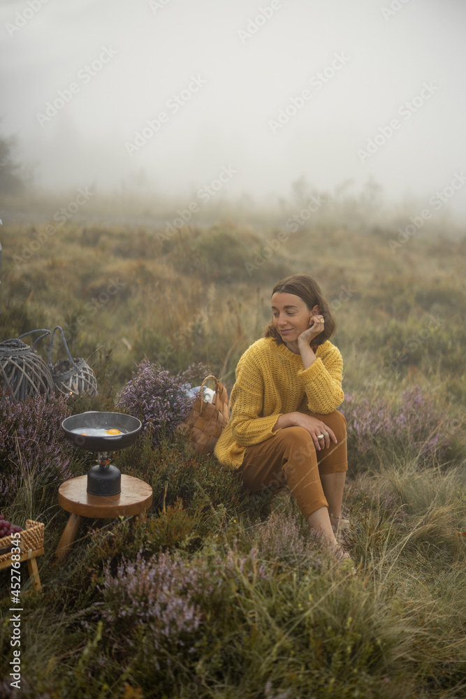 女旅行者在雾蒙蒙的wea山上旅行时准备早餐，在炉子上煎鸡蛋
