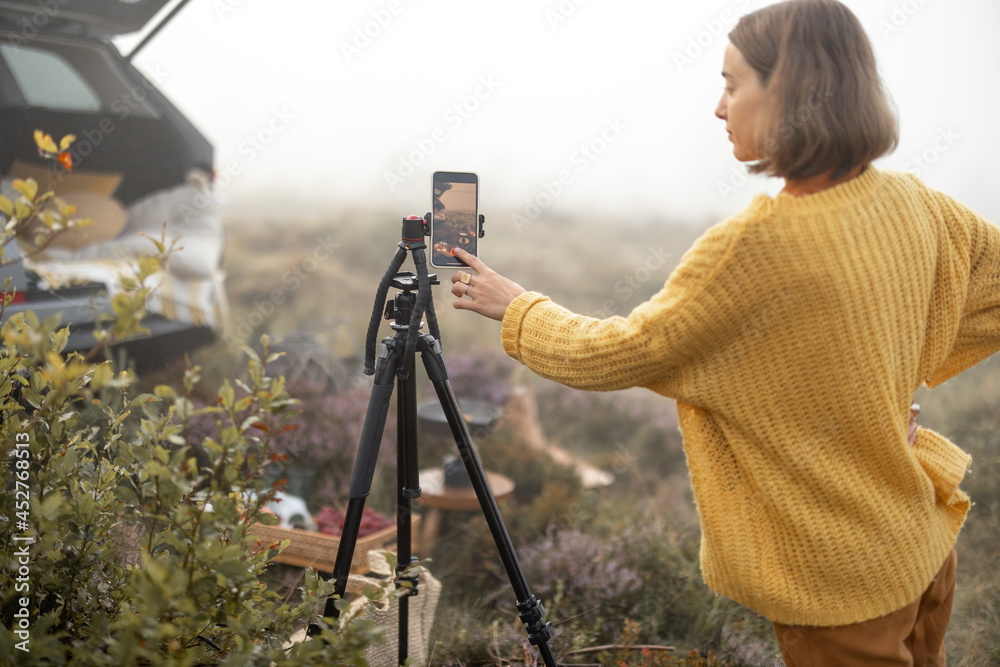 女旅行者在山上旅行时在野餐时通过电话拍摄视频