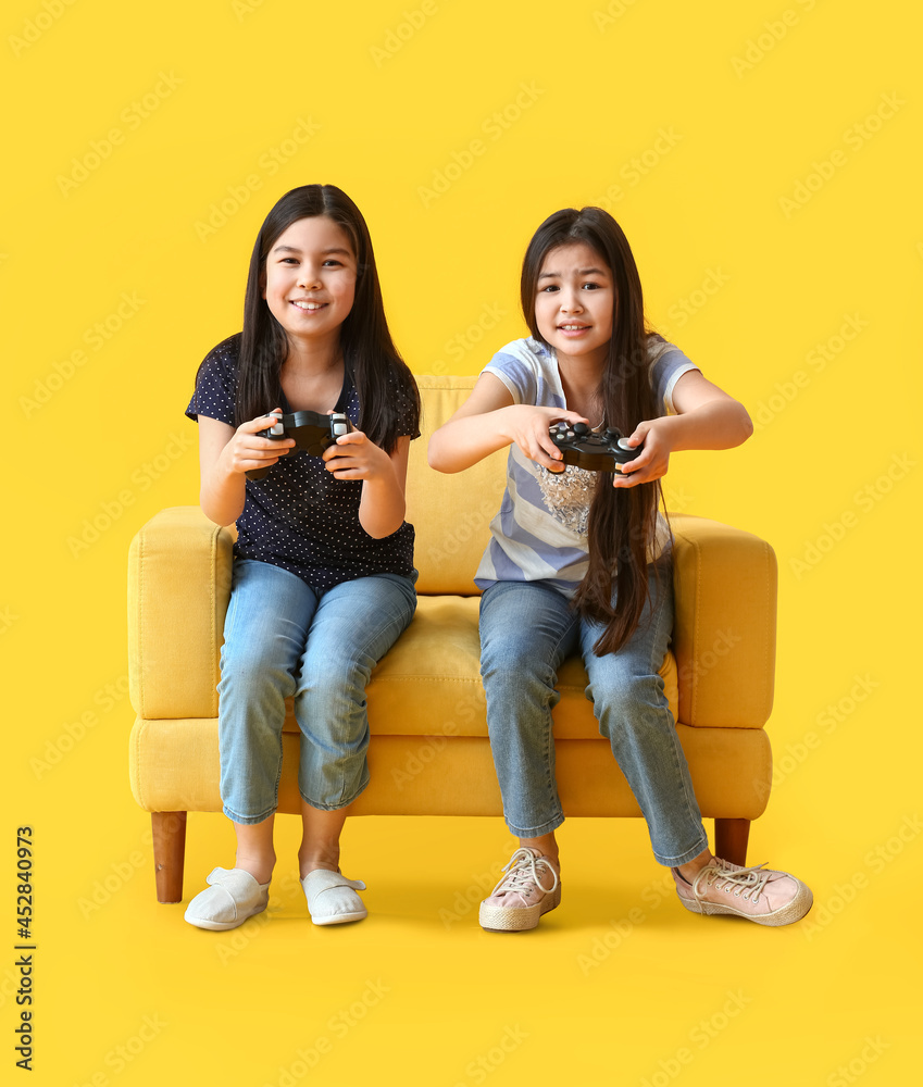 可爱的小姐妹在彩色背景下玩电子游戏