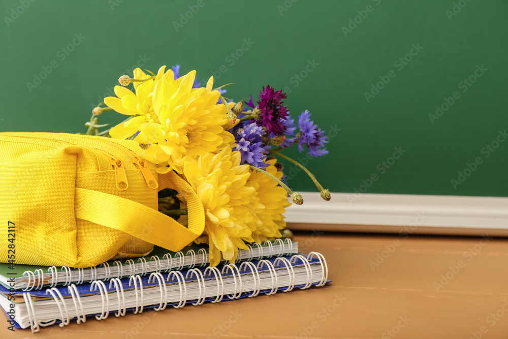 Beautiful flowers and stationery on table in classroom. Teachers Day celebration