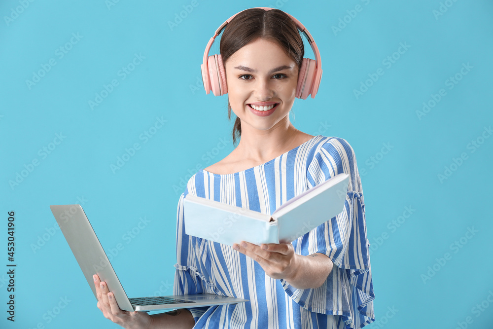 带笔记本电脑、书本和彩色背景耳机的年轻女性