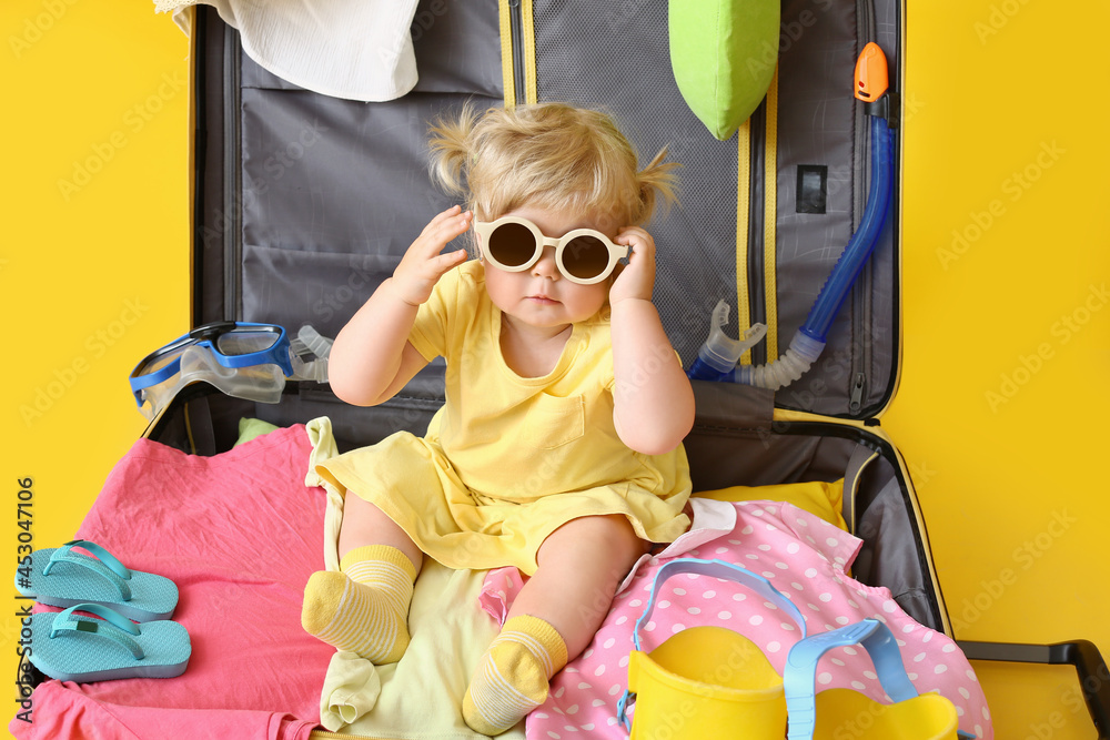 行李箱里的可爱女婴，背景是彩色物品