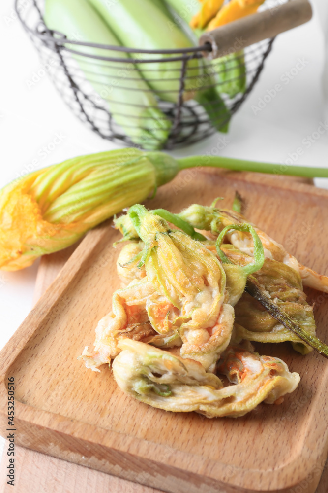 Board with fried zucchini flowers on table, closeup