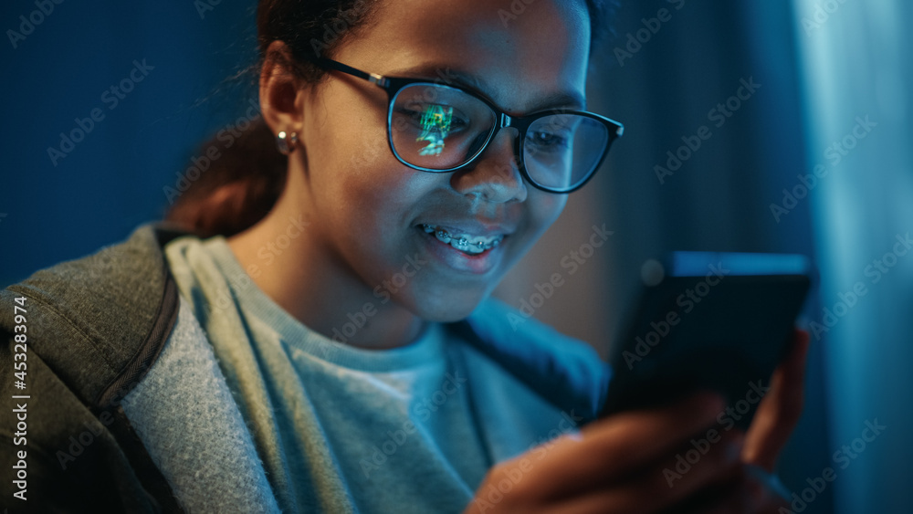 一个十几岁的多民族黑人女孩在智能手机应用程序上玩街机视频游戏的肖像