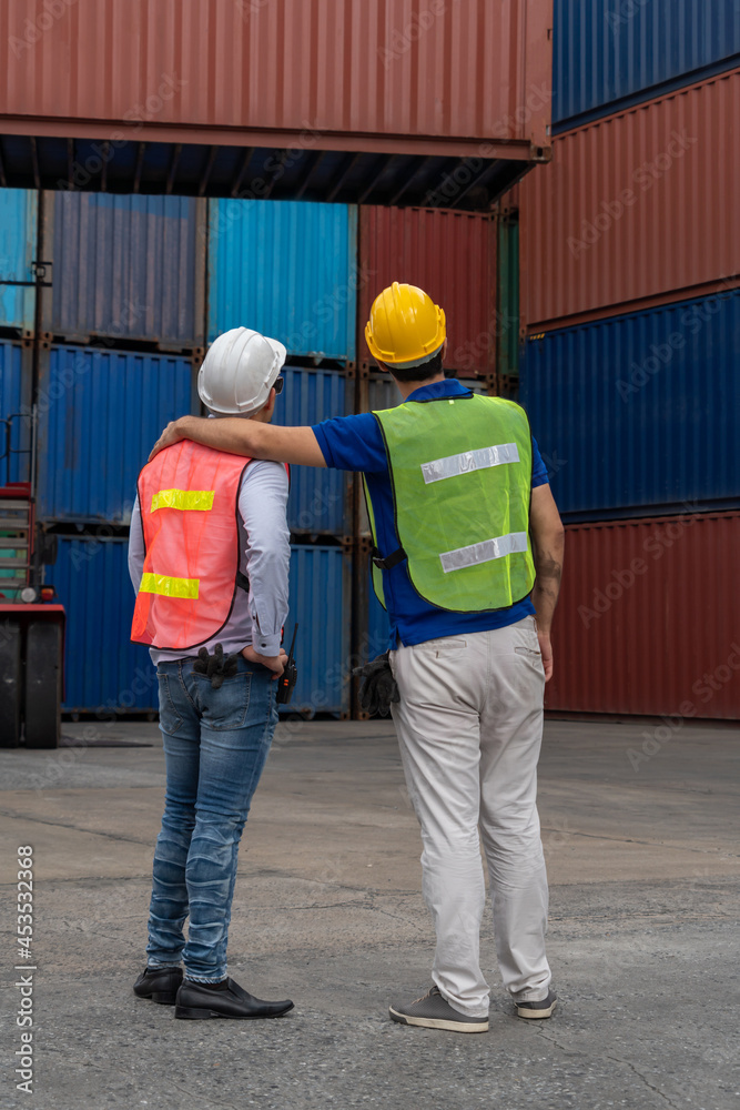 Industrial worker works with co-worker at overseas shipping container yard . Logistics supply chain 