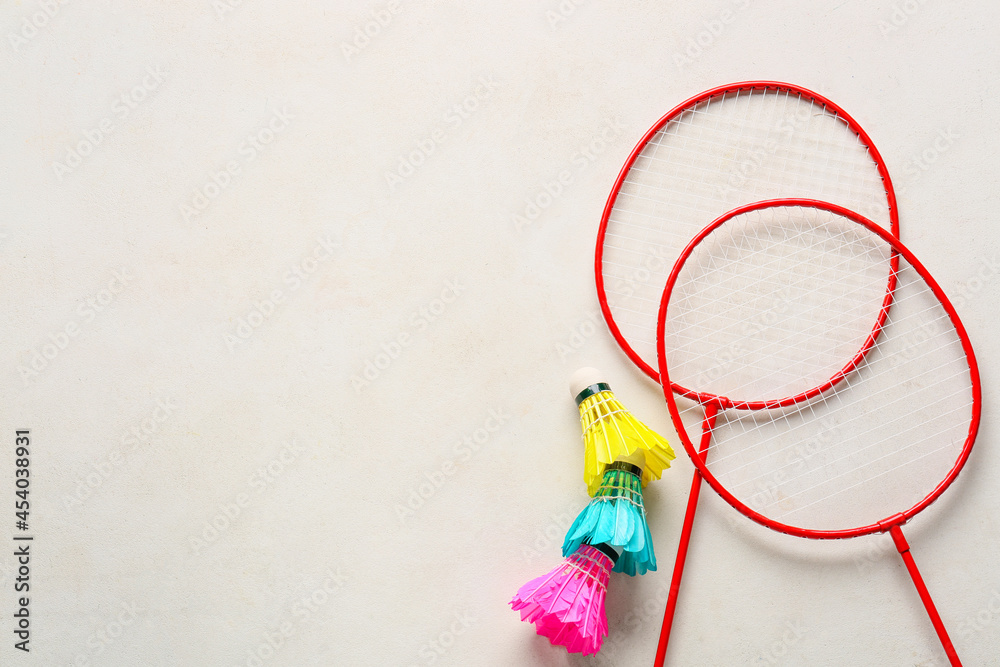 Badminton rackets and shuttlecocks on light background