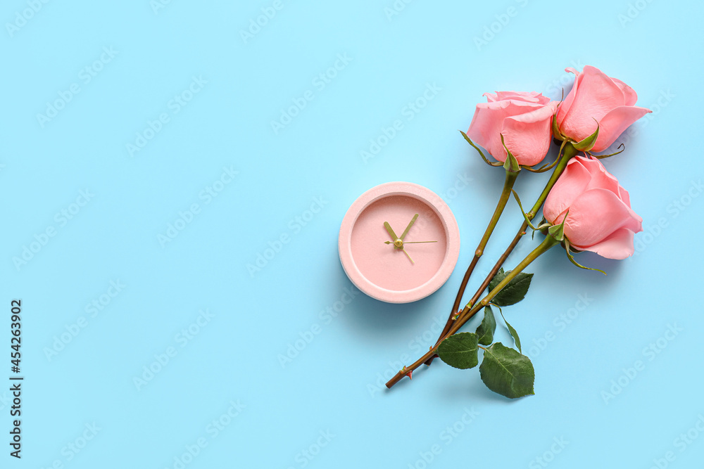 Alarm clock with rose flowers on color background