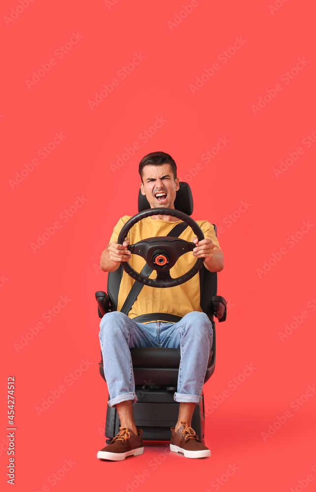 愤怒的男子坐在汽车座椅上，方向盘在彩色背景上