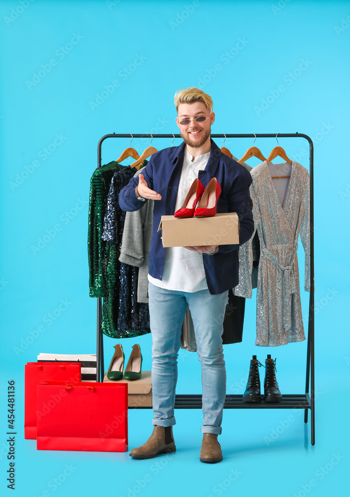 Male stylist with shoes on color background