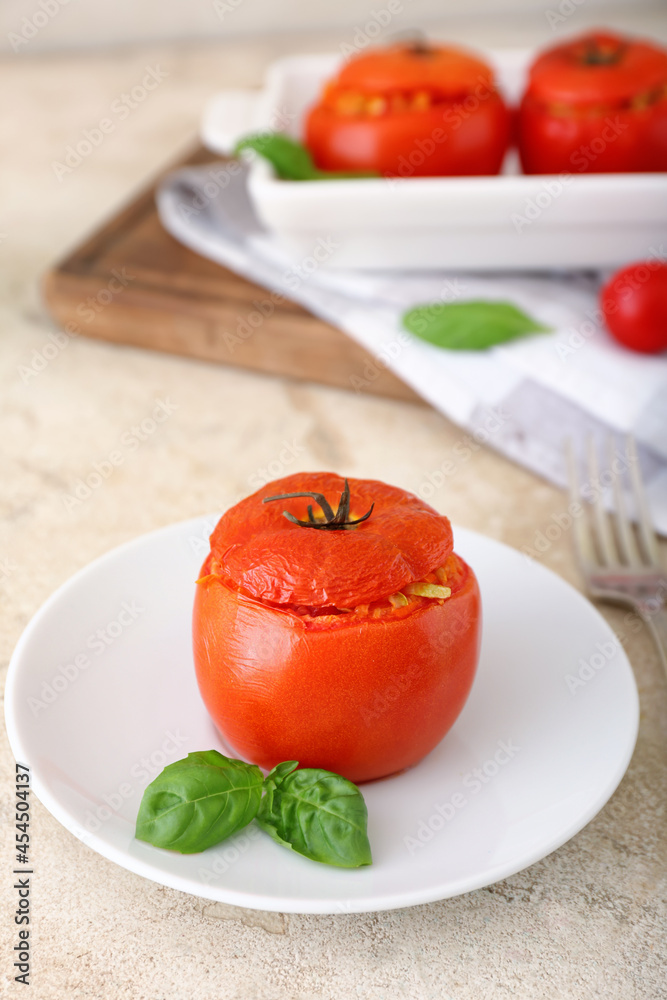 Plate with tasty stuffed tomato on light background