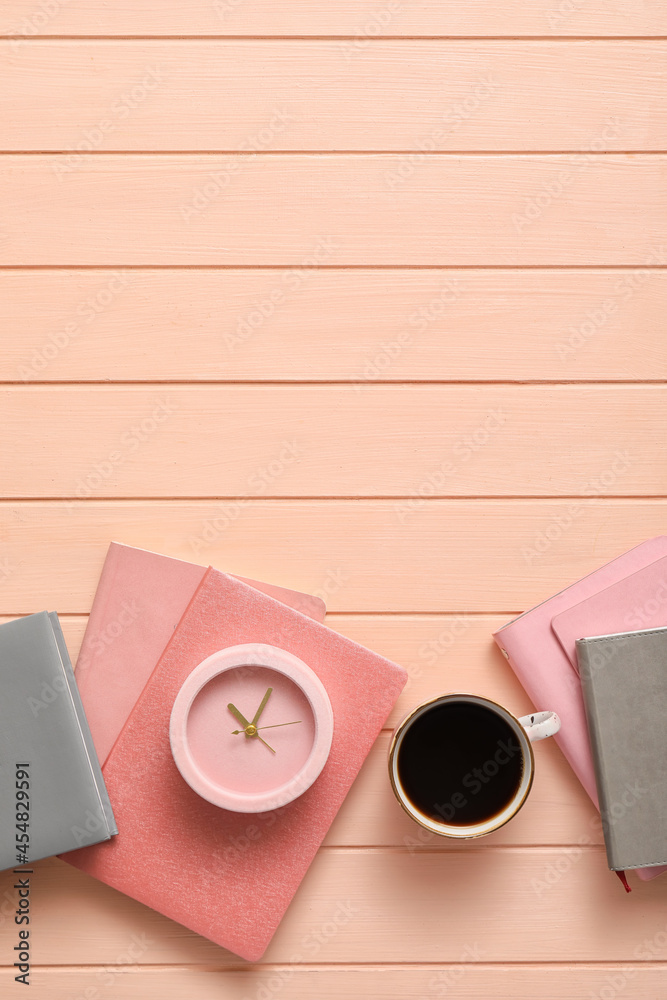 彩色木制背景的带笔记本和咖啡的闹钟